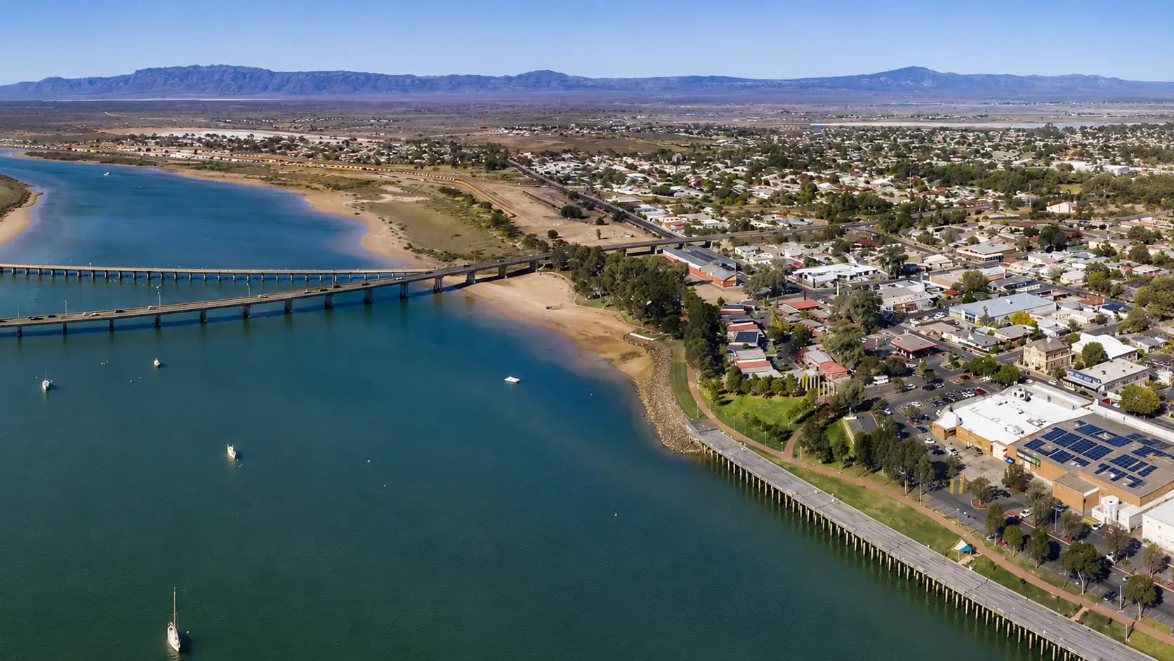 Aerial view of Port Augusta with the Joy Baluch Bridge over Spencer Gulf and the Flinders Ranges beyond